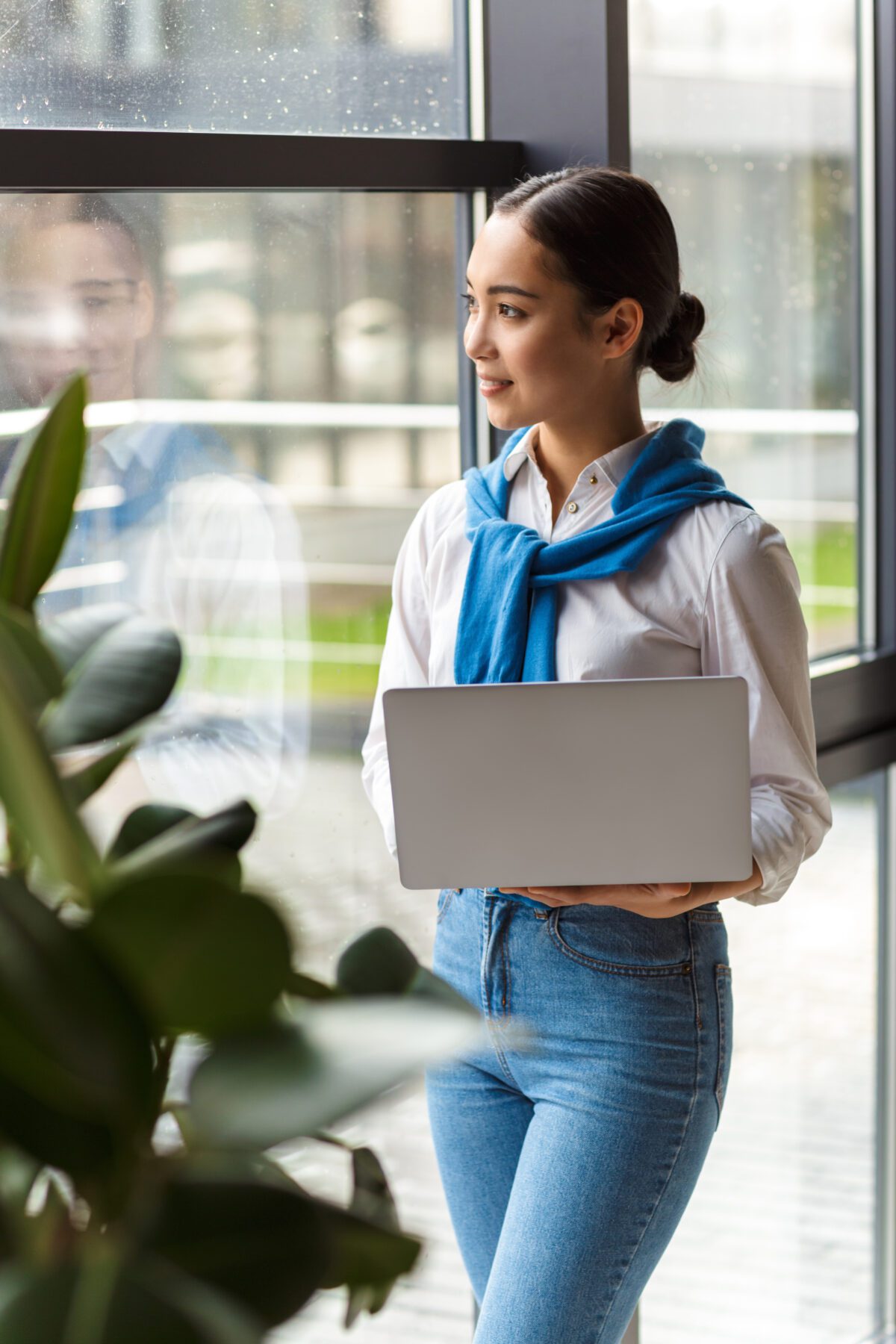 Image of asian secretary woman holding laptop computer by window